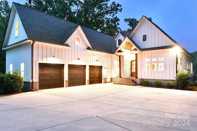 modern inspired farmhouse featuring concrete driveway, board and batten siding, an attached garage, and roof with shingles