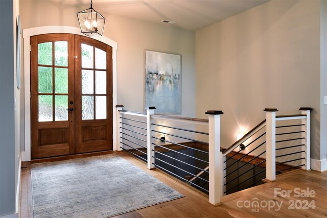 foyer featuring a chandelier, french doors, visible vents, and wood finished floors