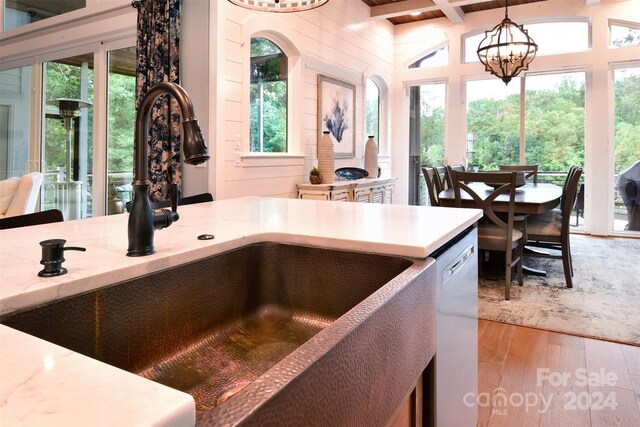 kitchen featuring dishwasher, light countertops, a sink, and decorative light fixtures