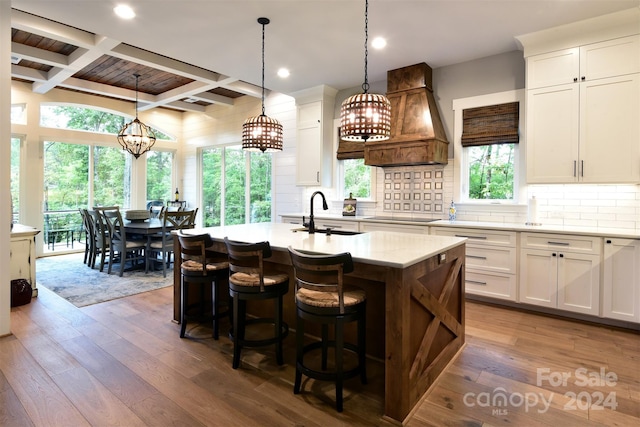 kitchen featuring white cabinets, a sink, and an island with sink