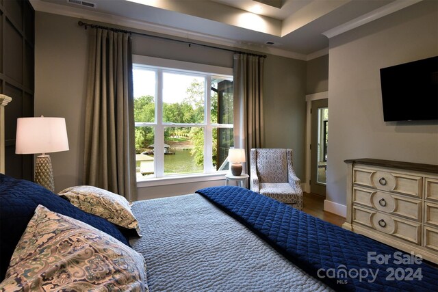 bedroom featuring baseboards, wood finished floors, visible vents, and crown molding