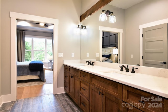 ensuite bathroom featuring wood finished floors, double vanity, a sink, and ensuite bathroom