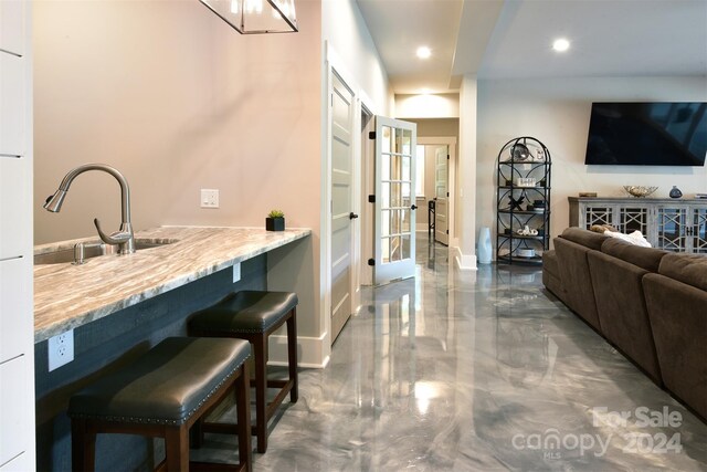 bar with recessed lighting, marble finish floor, a sink, and baseboards