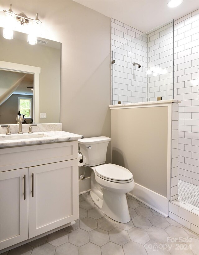 bathroom with toilet, walk in shower, vanity, and tile patterned floors