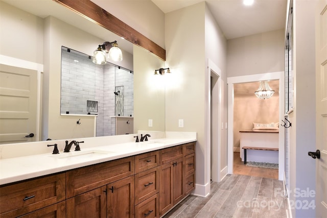 bathroom with a walk in shower, wood finished floors, a sink, and double vanity