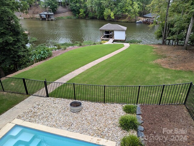 view of yard featuring a fire pit, a water view, and fence