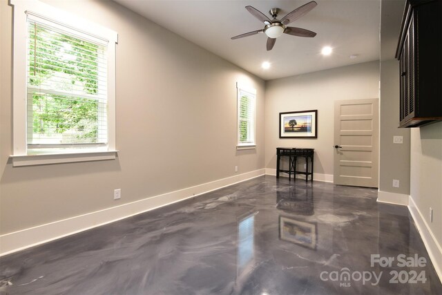 unfurnished living room with baseboards, concrete floors, and a healthy amount of sunlight