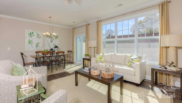 living room with plenty of natural light, hardwood / wood-style flooring, crown molding, and a notable chandelier