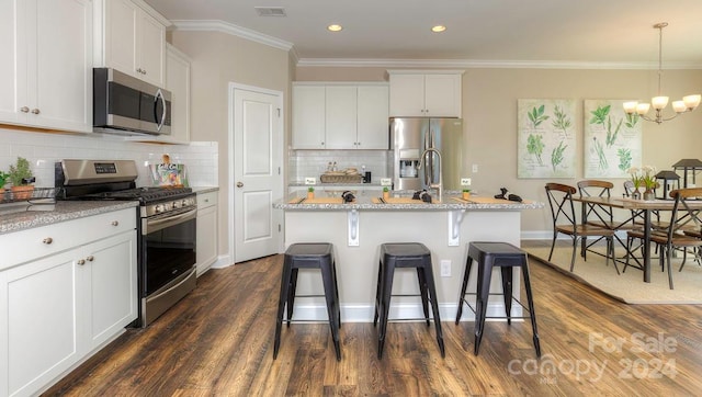 kitchen featuring appliances with stainless steel finishes, a chandelier, white cabinetry, and a kitchen island with sink