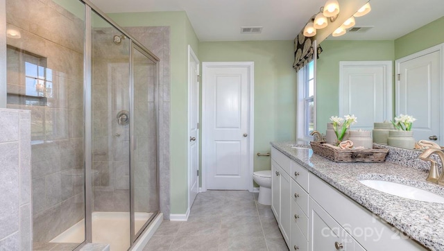 bathroom with toilet, vanity, tile patterned flooring, and a shower with door