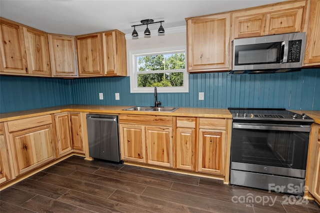 kitchen with wood tiled floor, stainless steel appliances, light countertops, light brown cabinets, and a sink