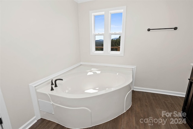 full bathroom with a garden tub, baseboards, and wood finished floors