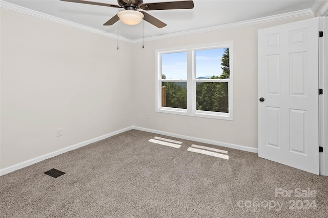 carpeted spare room with visible vents, crown molding, baseboards, and ceiling fan