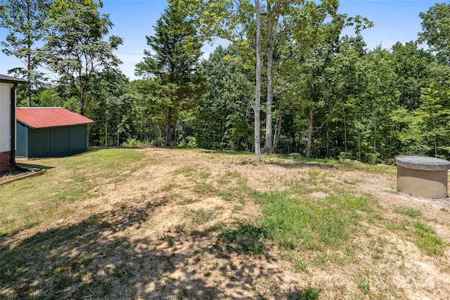 view of yard with an outdoor structure and a wooded view