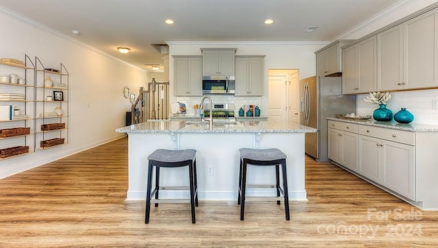 kitchen with gray cabinetry, decorative backsplash, a center island with sink, and sink