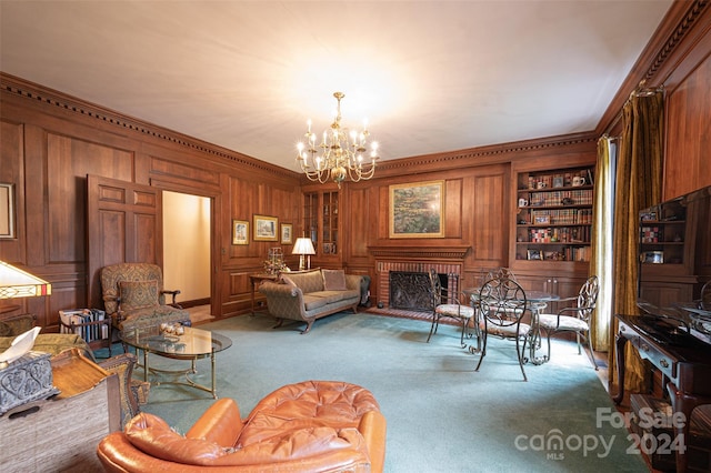 carpeted living room featuring built in shelves, ornamental molding, a notable chandelier, and a fireplace