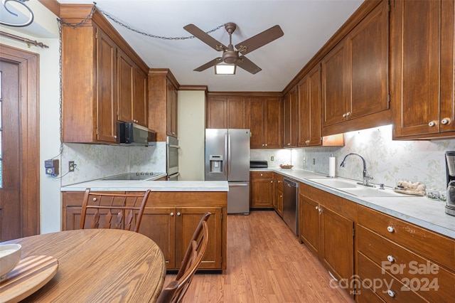 kitchen featuring ceiling fan, appliances with stainless steel finishes, decorative backsplash, light wood-type flooring, and sink