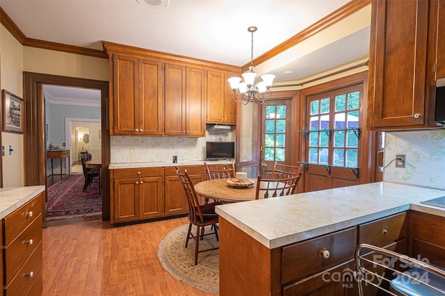 kitchen with decorative light fixtures, light hardwood / wood-style floors, a chandelier, and tasteful backsplash