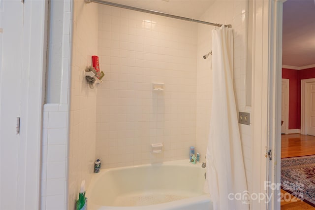 bathroom featuring crown molding, wood-type flooring, and shower / bath combo with shower curtain