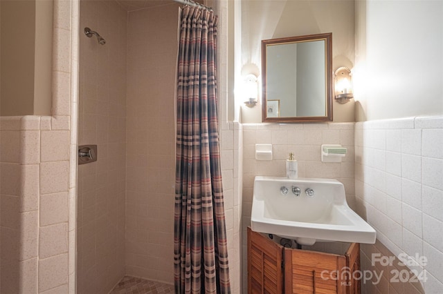 bathroom with tile walls, a shower with curtain, and sink