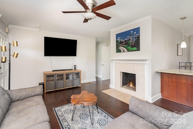 living room featuring a fireplace, ceiling fan, crown molding, and dark hardwood / wood-style floors