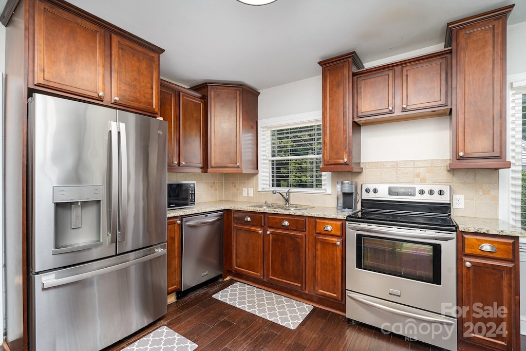 kitchen featuring sink, dark wood-type flooring, light stone countertops, tasteful backsplash, and stainless steel appliances