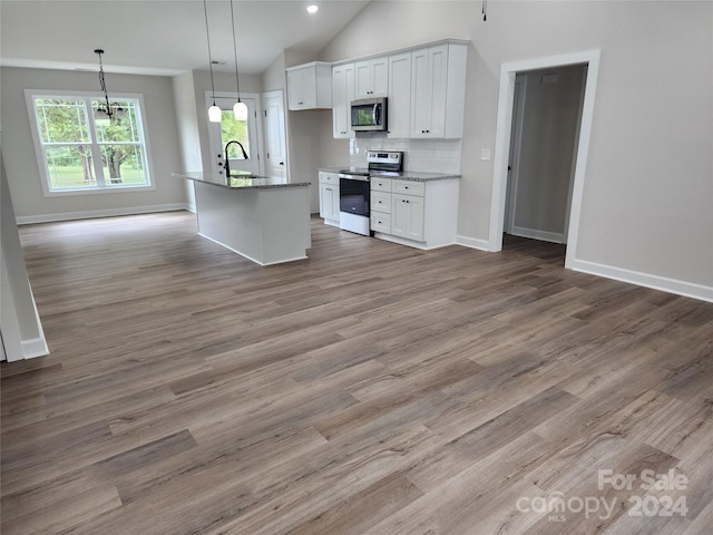 kitchen featuring white cabinets, a center island with sink, hardwood / wood-style flooring, vaulted ceiling, and stainless steel appliances