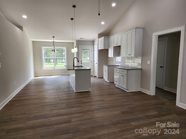 kitchen with a kitchen island with sink, decorative light fixtures, backsplash, and dark hardwood / wood-style flooring