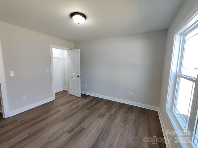 unfurnished bedroom featuring a closet, wood finished floors, and baseboards