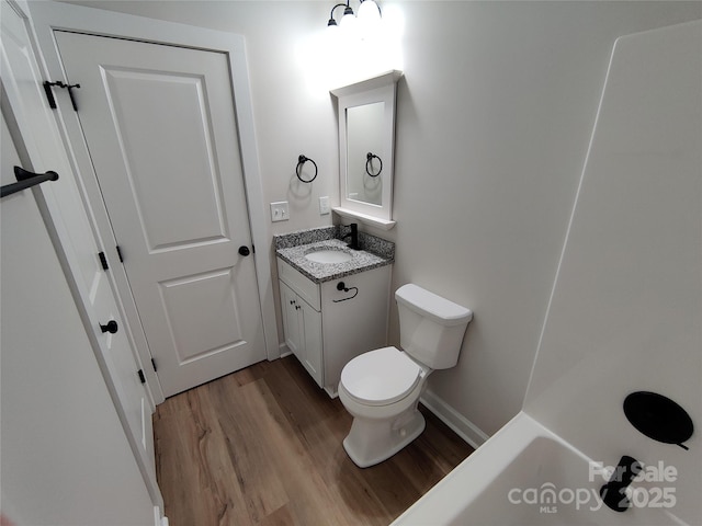 bathroom featuring toilet, baseboards, wood finished floors, and vanity