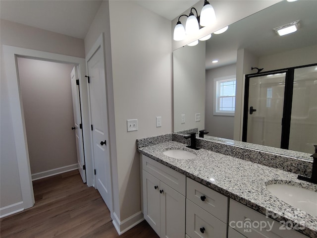 bathroom featuring baseboards, wood finished floors, a sink, and a shower stall