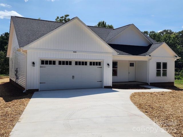 modern farmhouse with concrete driveway, roof with shingles, and an attached garage