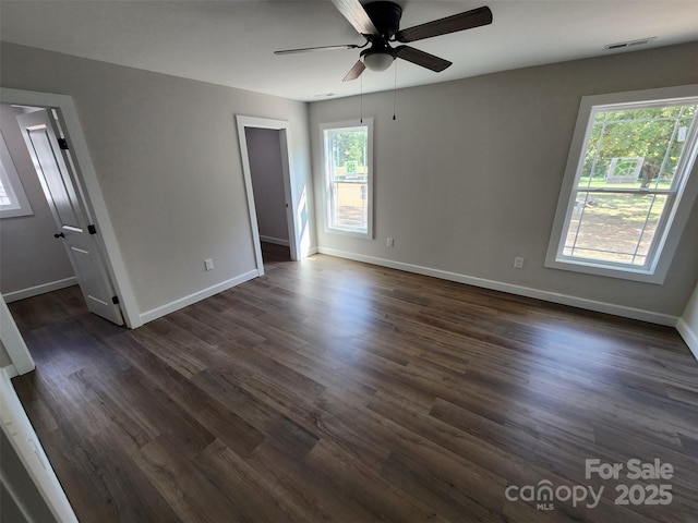 spare room with dark wood-style flooring, visible vents, a healthy amount of sunlight, and a ceiling fan