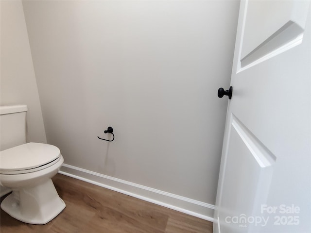 bathroom with toilet, baseboards, and wood finished floors