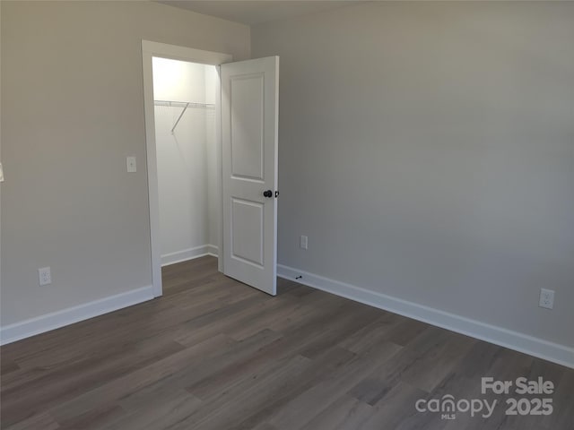 empty room with dark wood-style flooring and baseboards
