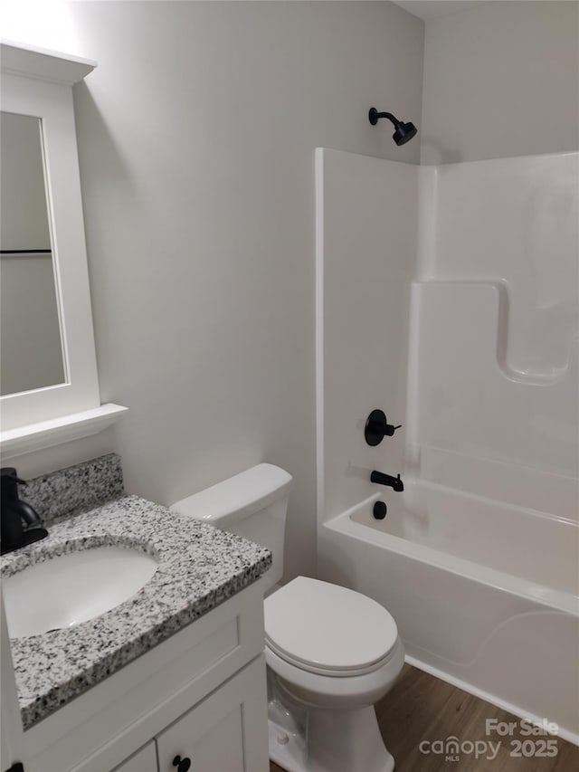 bathroom featuring toilet, vanity, tub / shower combination, and wood finished floors