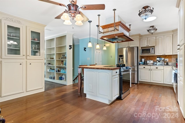 kitchen featuring a kitchen island, light hardwood / wood-style flooring, ornamental molding, pendant lighting, and stainless steel appliances