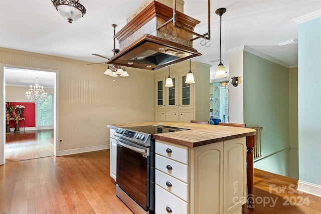 kitchen featuring stainless steel electric stove, hanging light fixtures, wooden counters, ornamental molding, and a kitchen island