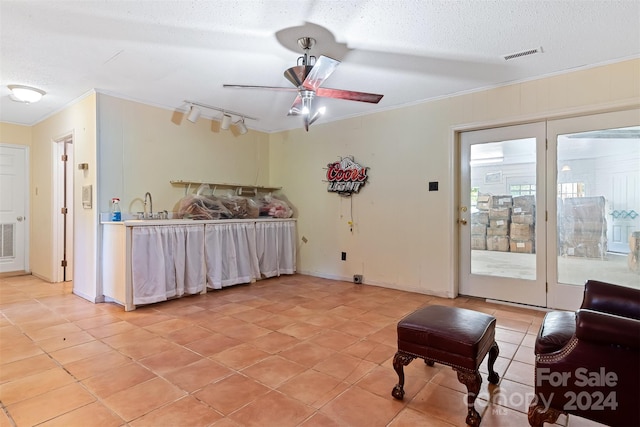 tiled living room with ceiling fan, sink, track lighting, a textured ceiling, and ornamental molding