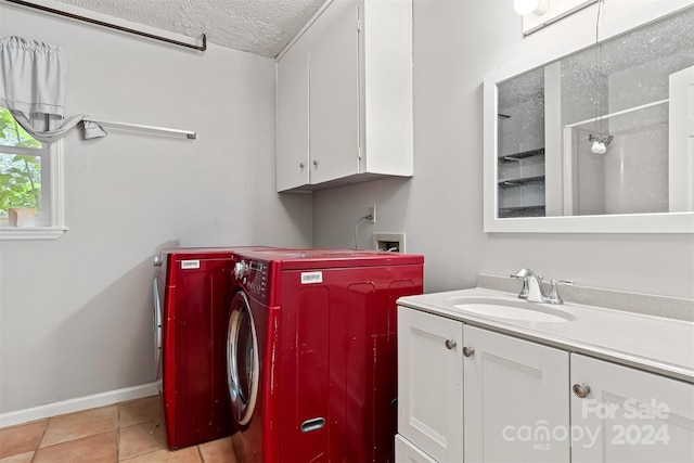 washroom with washer / clothes dryer, a textured ceiling, light tile patterned floors, sink, and cabinets