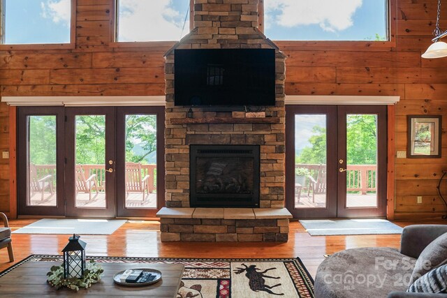 living room with wood walls, wood-type flooring, a healthy amount of sunlight, and french doors