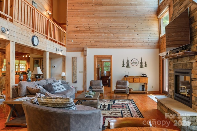 living room featuring high vaulted ceiling, wooden ceiling, light hardwood / wood-style flooring, and a fireplace