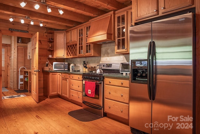 kitchen with premium range hood, decorative backsplash, beamed ceiling, light wood-type flooring, and appliances with stainless steel finishes