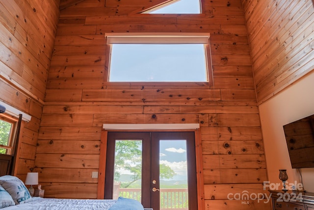 bedroom featuring access to outside, french doors, wooden walls, and multiple windows