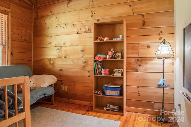 bedroom featuring light hardwood / wood-style floors and wood walls