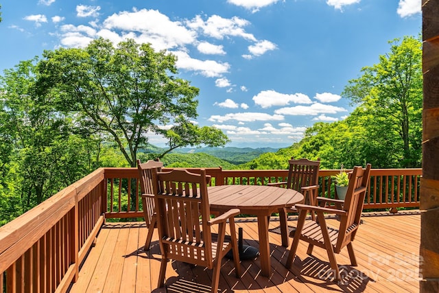 wooden deck with outdoor dining space and a mountain view