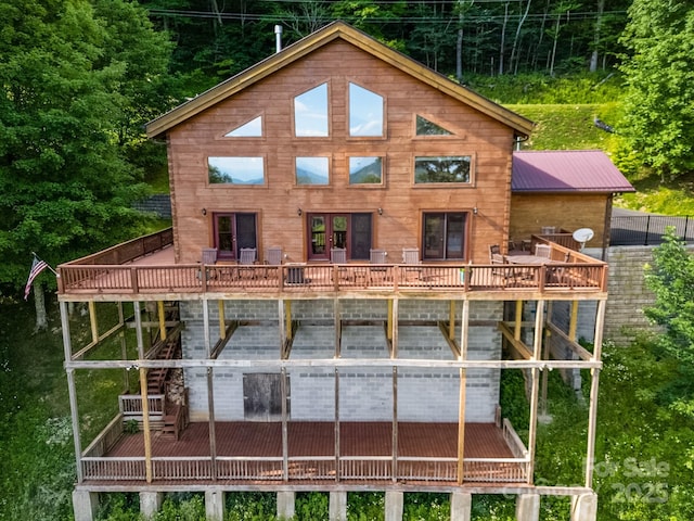 rear view of property with metal roof, a wooden deck, and stairs