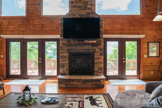 living room with wooden walls, a wealth of natural light, french doors, and wood finished floors