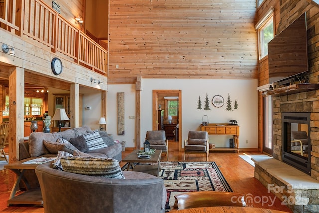 living area with baseboards, a stone fireplace, light wood finished floors, and a towering ceiling