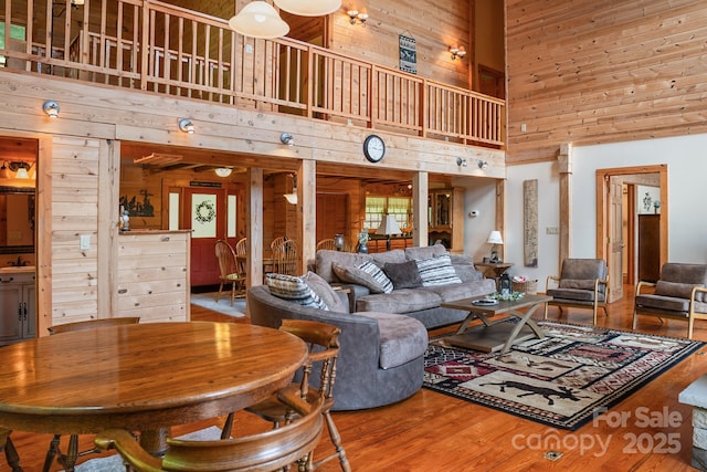 living room featuring wooden walls, wood finished floors, and a towering ceiling